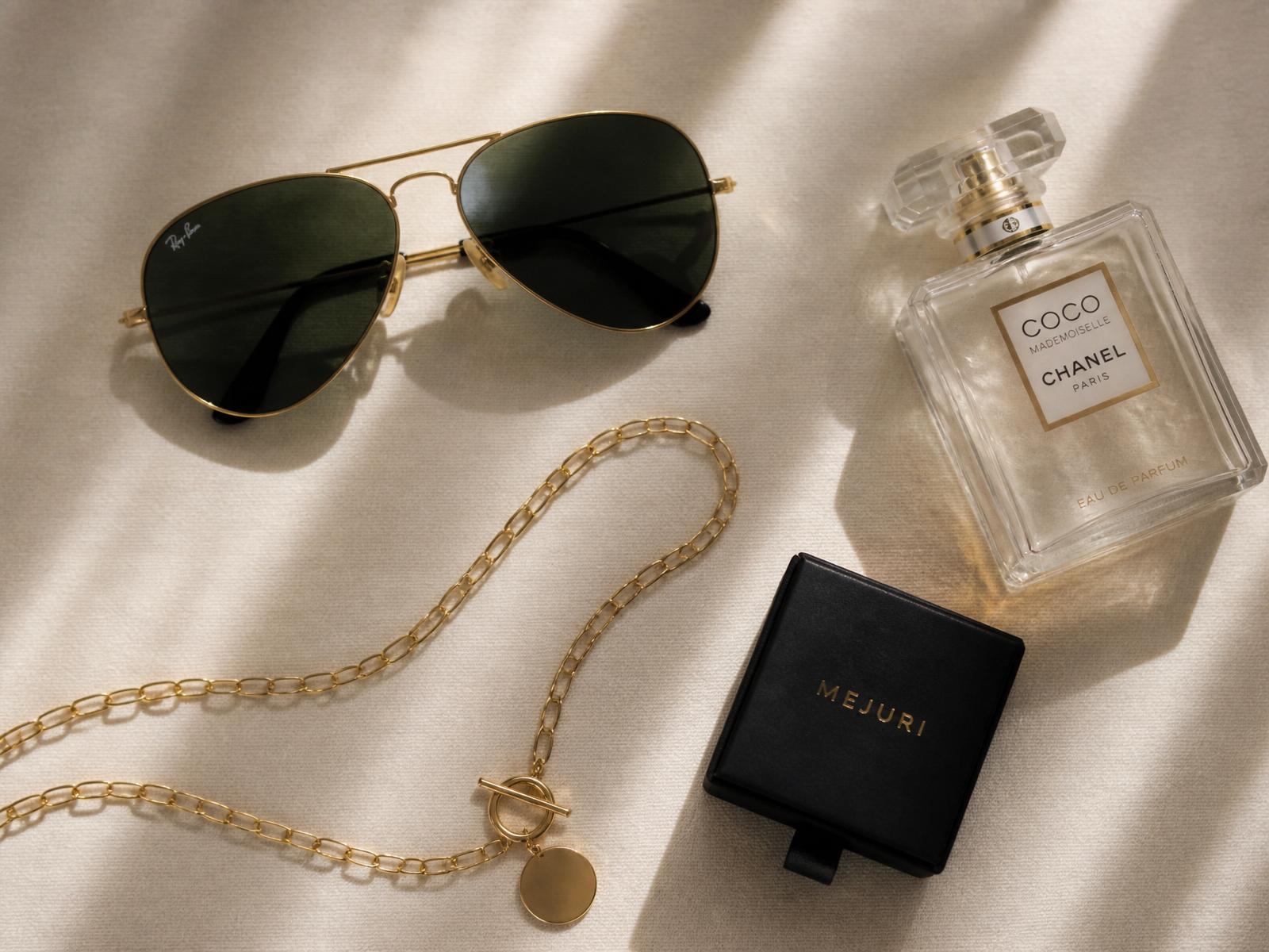 Luxury flatlay of sunglasses, jewelry, and perfume